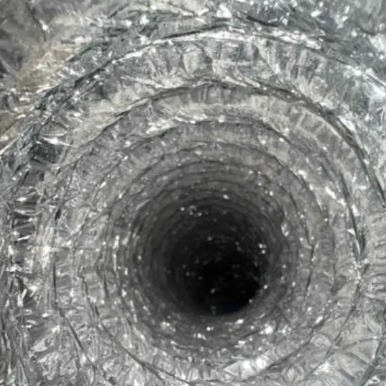 The inside of a cleaned dryer vent duct: bare foil walls and a clear run all the way down