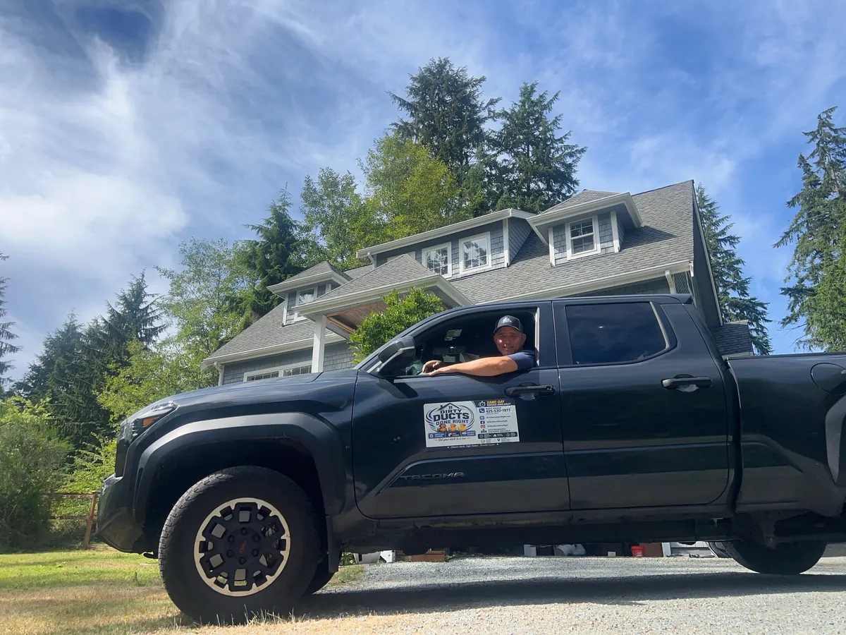 Nate Hager at a customer's house, leaning out of his Dirty Ducts Done Right truck